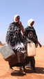 Two women carrying water containers representing communities we help through the Emergency Hunger relief Project,