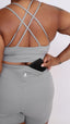 Person wearing a gray sports bra and shorts with cross back and hidden pocket.