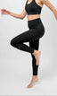 Woman wearing sustainable black athletic leggings and supportive sports bra 